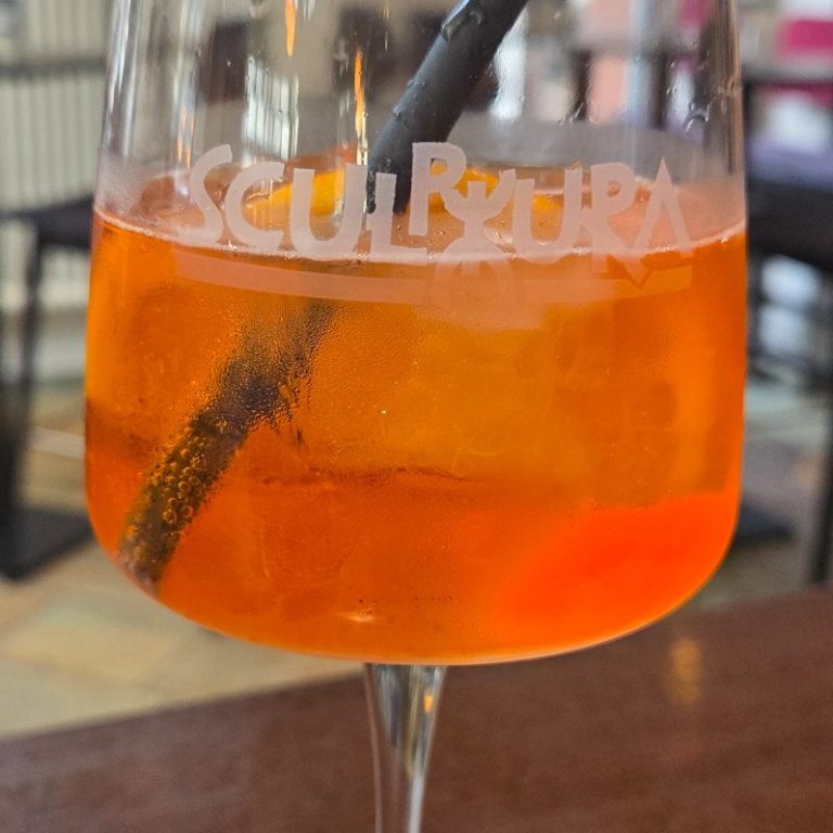 Sex on the beach Cocktail Cocktail mit orangefarbener Garnitur und Minzblatt auf einem Tisch.
